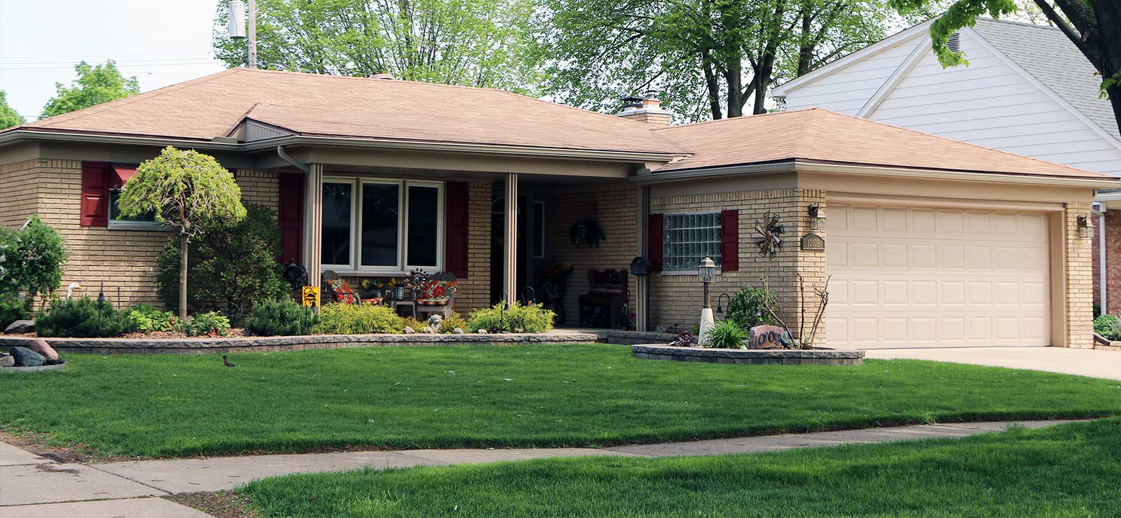 A street view photo of a house and front lawn with garden