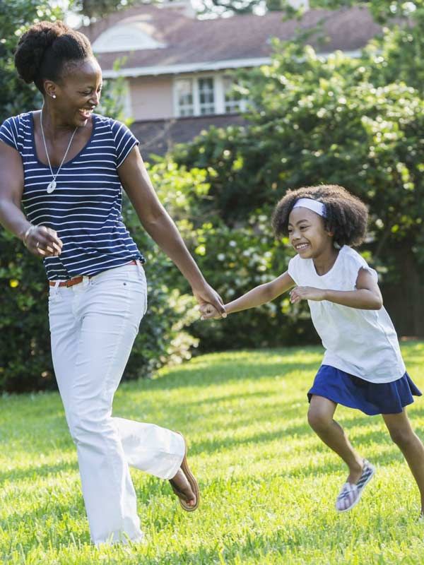 An adult woman holding hands with a young child