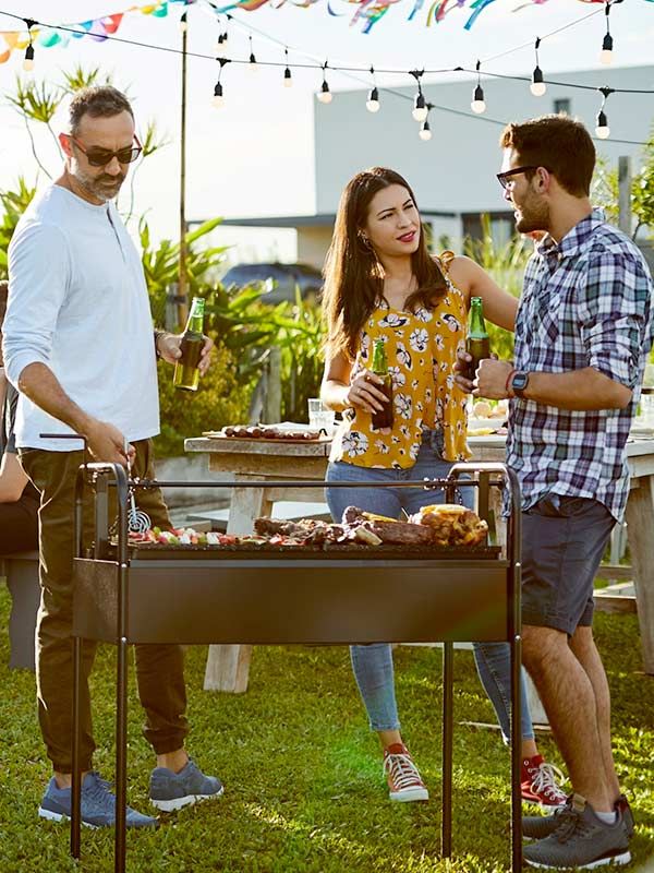 Three people conversing around a grill at a cookout